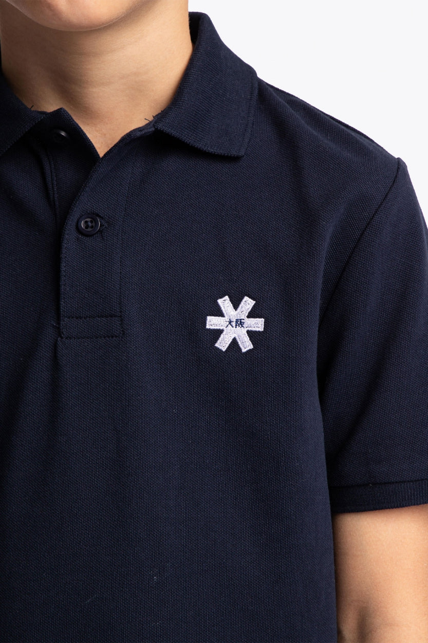 Osaka kids polo in navy with logo in white. Detail view logo