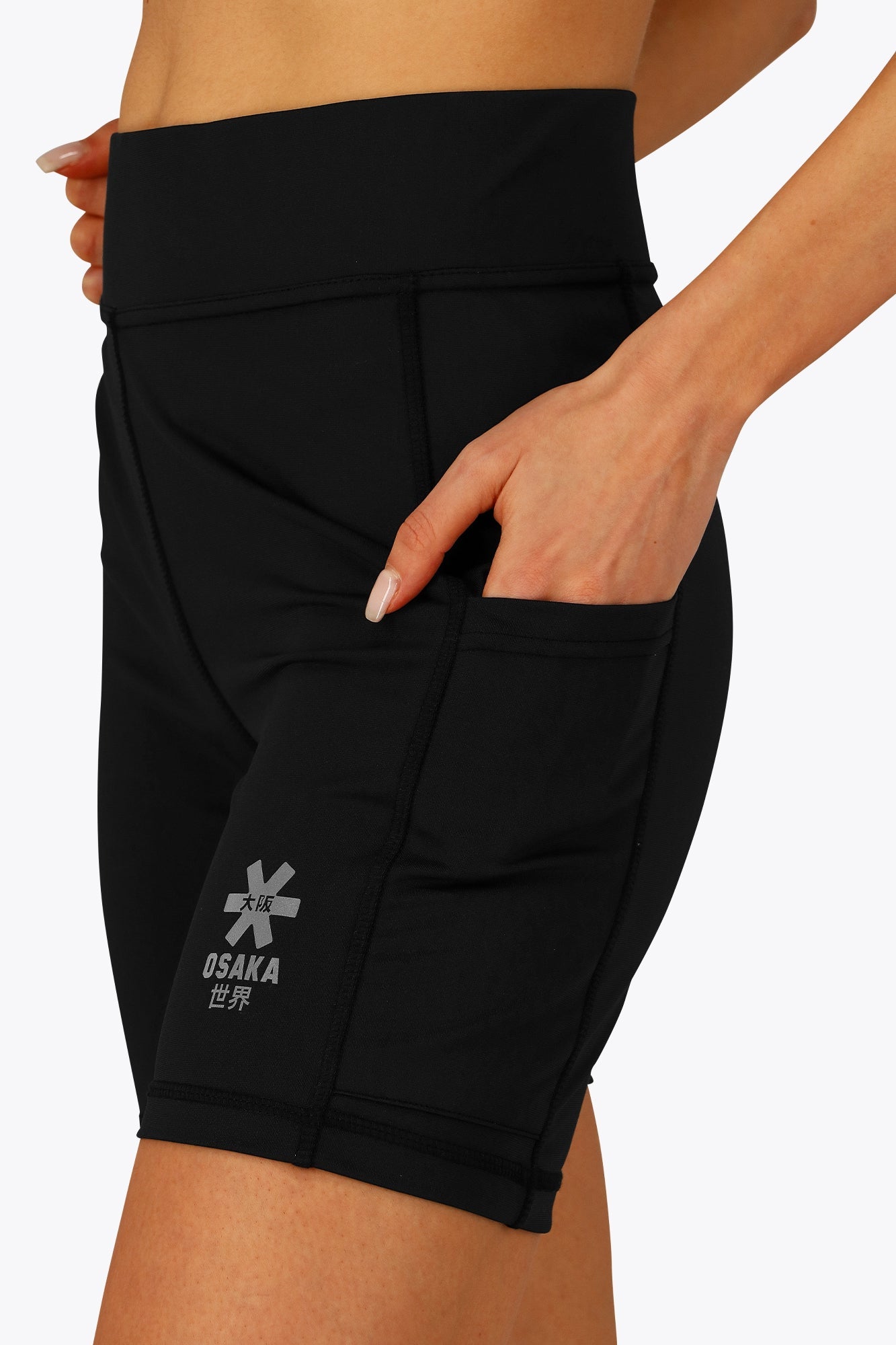 Woman wearing the Osaka women tech short thights in black with grey logo. Front detail pocket view