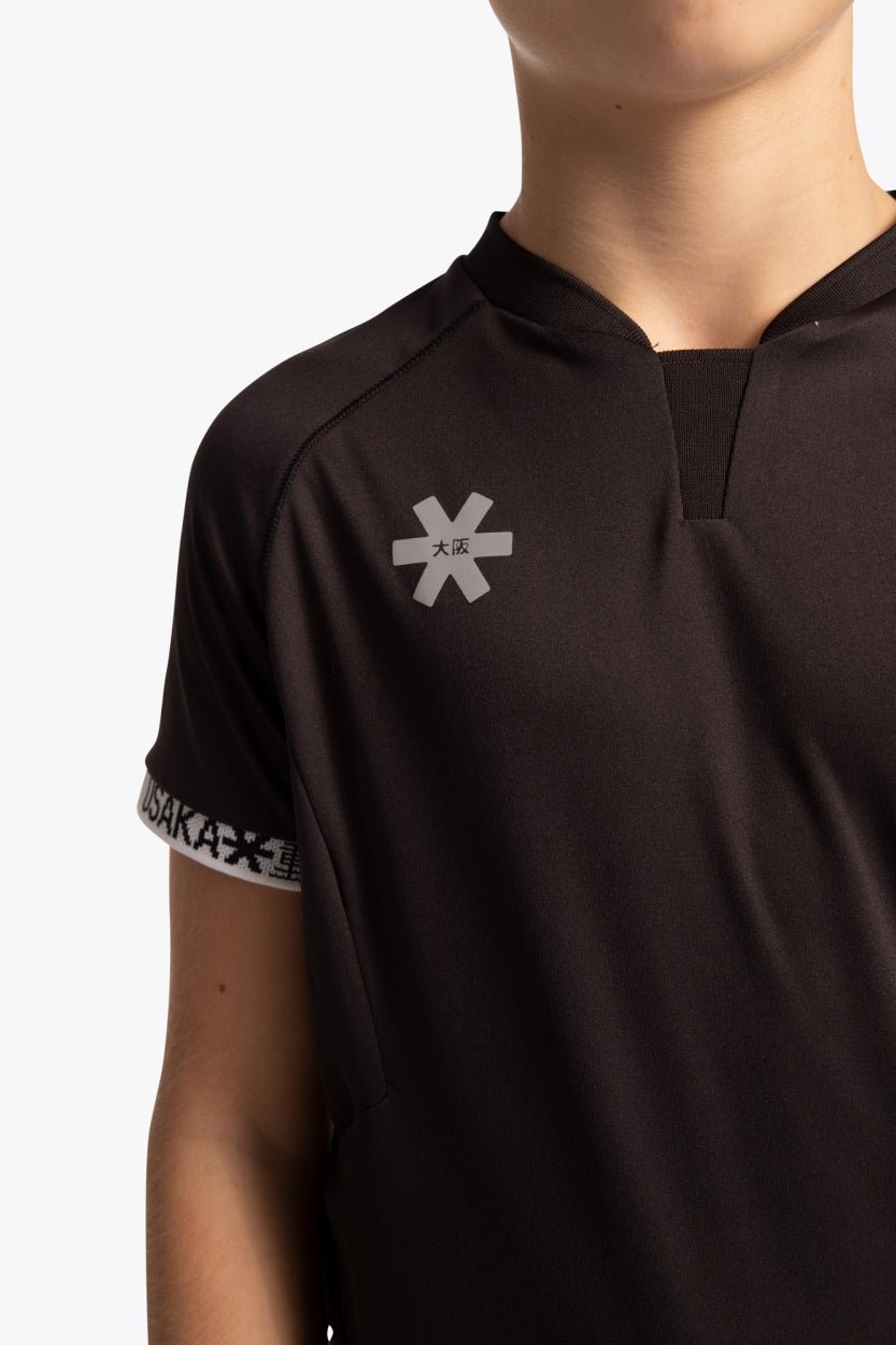 Boy wearing the Osaka Kids Jersey in Black. Front detail logoview