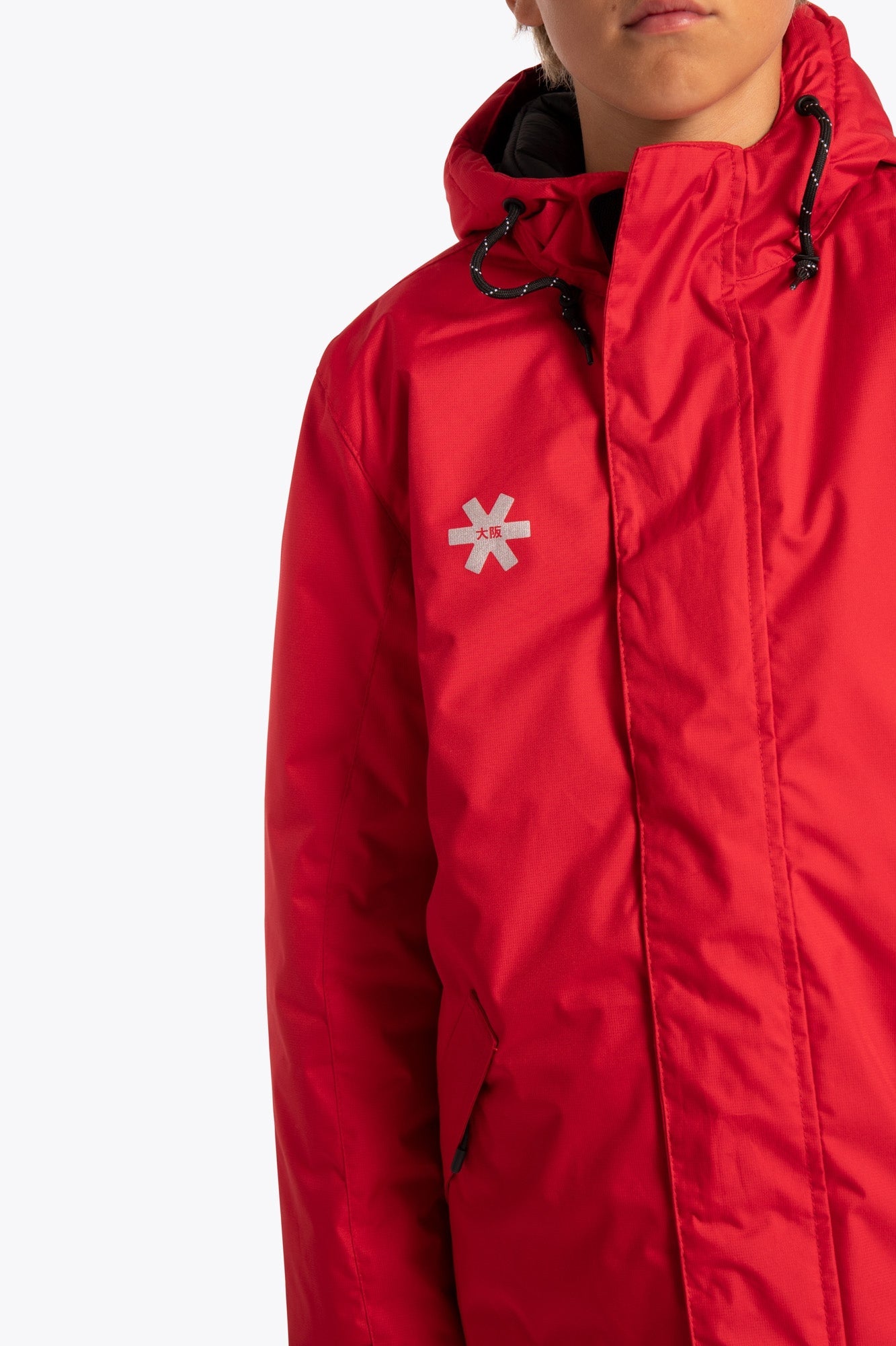 Boy wearing the Osaka Kids Stadium Jacket in Red. Front detail logo view