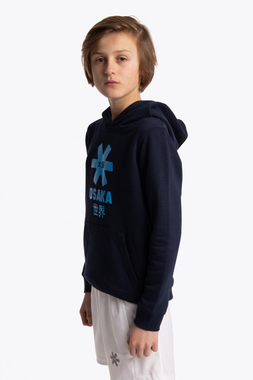 Boy wearing the Osaka kids hoodie in navy with blue star logo. Front/side view