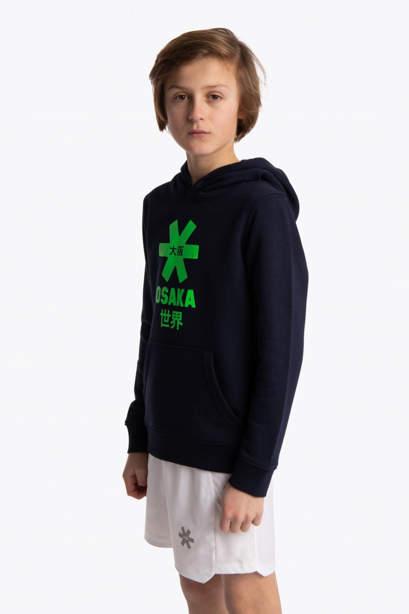 Boy wearing the Osaka kids hoodie in navy with green star logo. Front/side view
