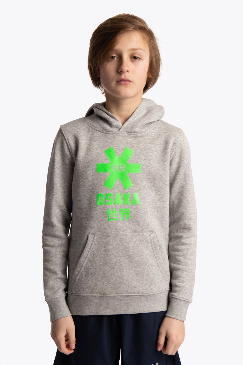 Boy wearing the Osaka kids hoodie in grey with green star logo. Front view