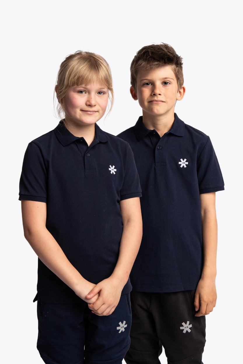 Boy and girl wearing the Osaka kids polo in navy with logo in white. Front view