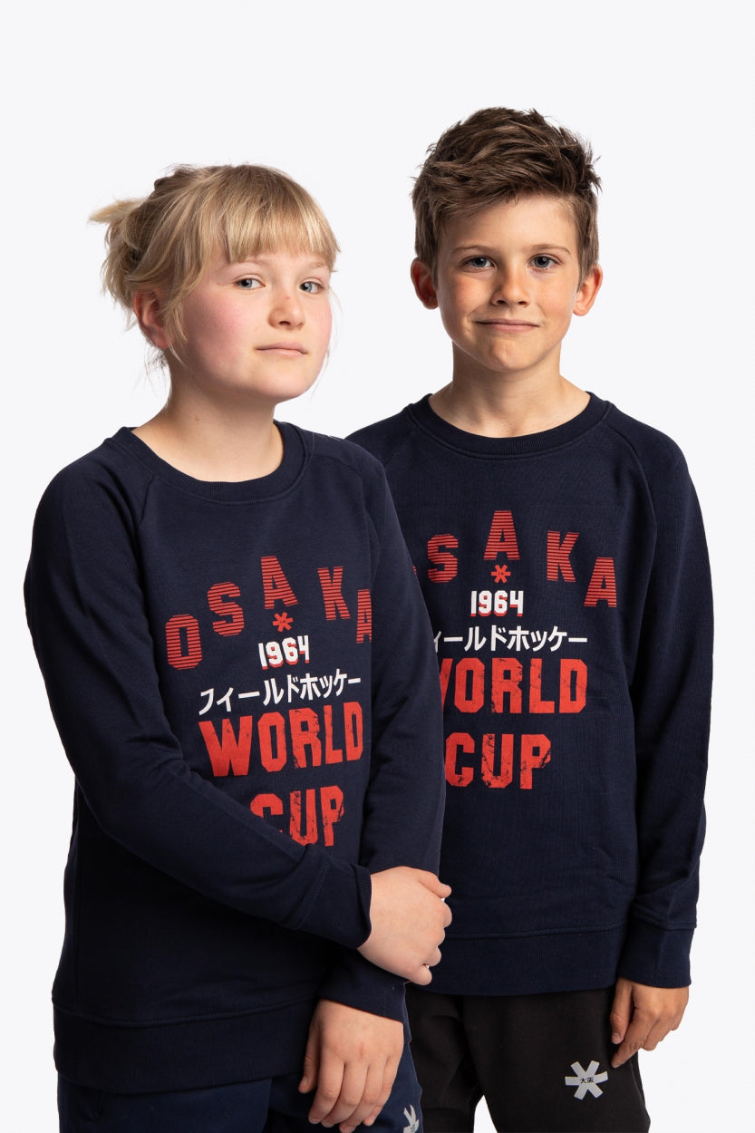Boy and girl wearing the Osaka kids worldcup sweater in navy with orange logo. Front view