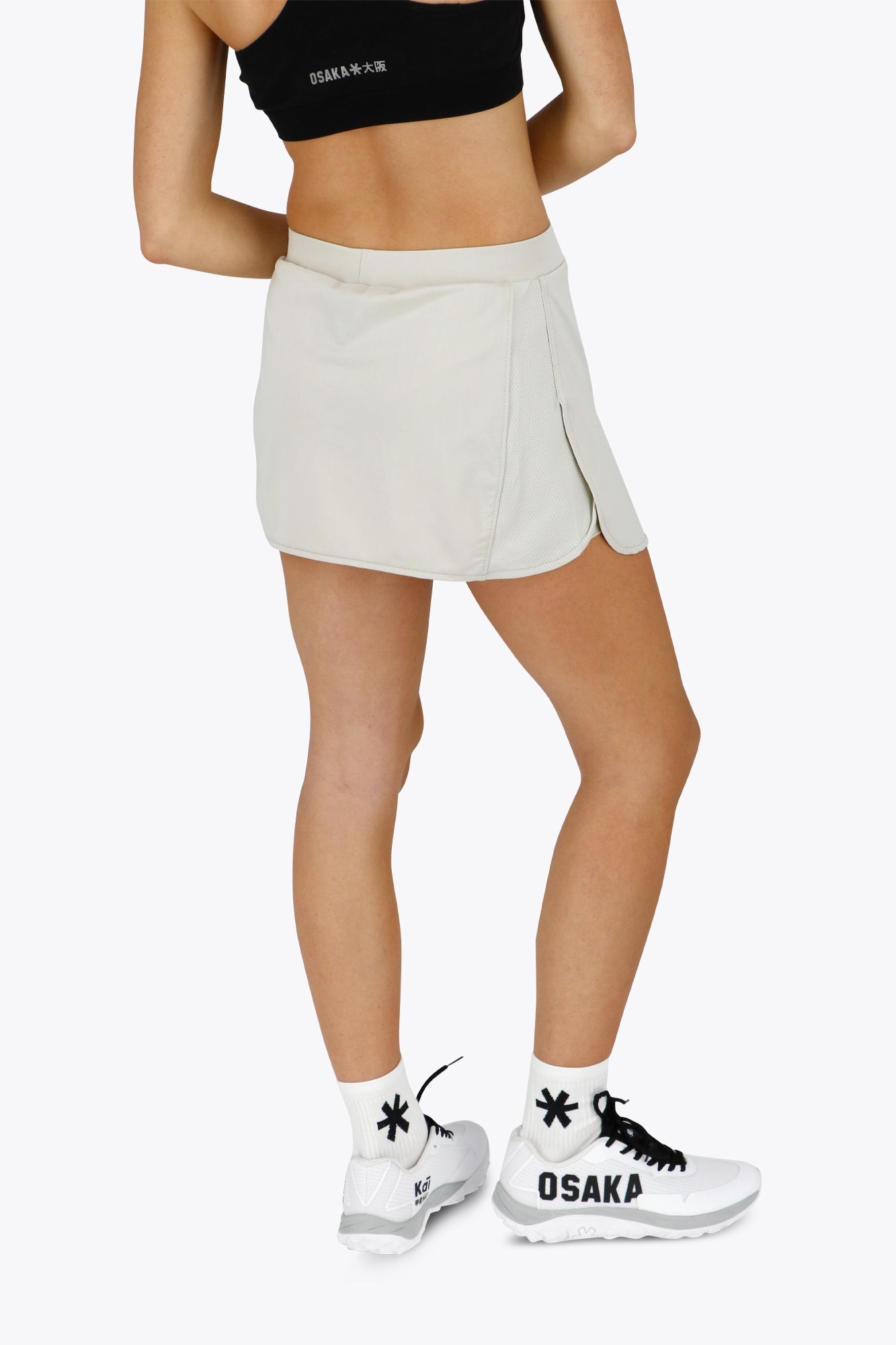 Woman wearing the Osaka women ball skort in light grey with logo in grey. Back view