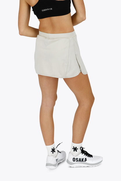 Woman wearing the Osaka women ball skort in light grey with logo in grey. Back view