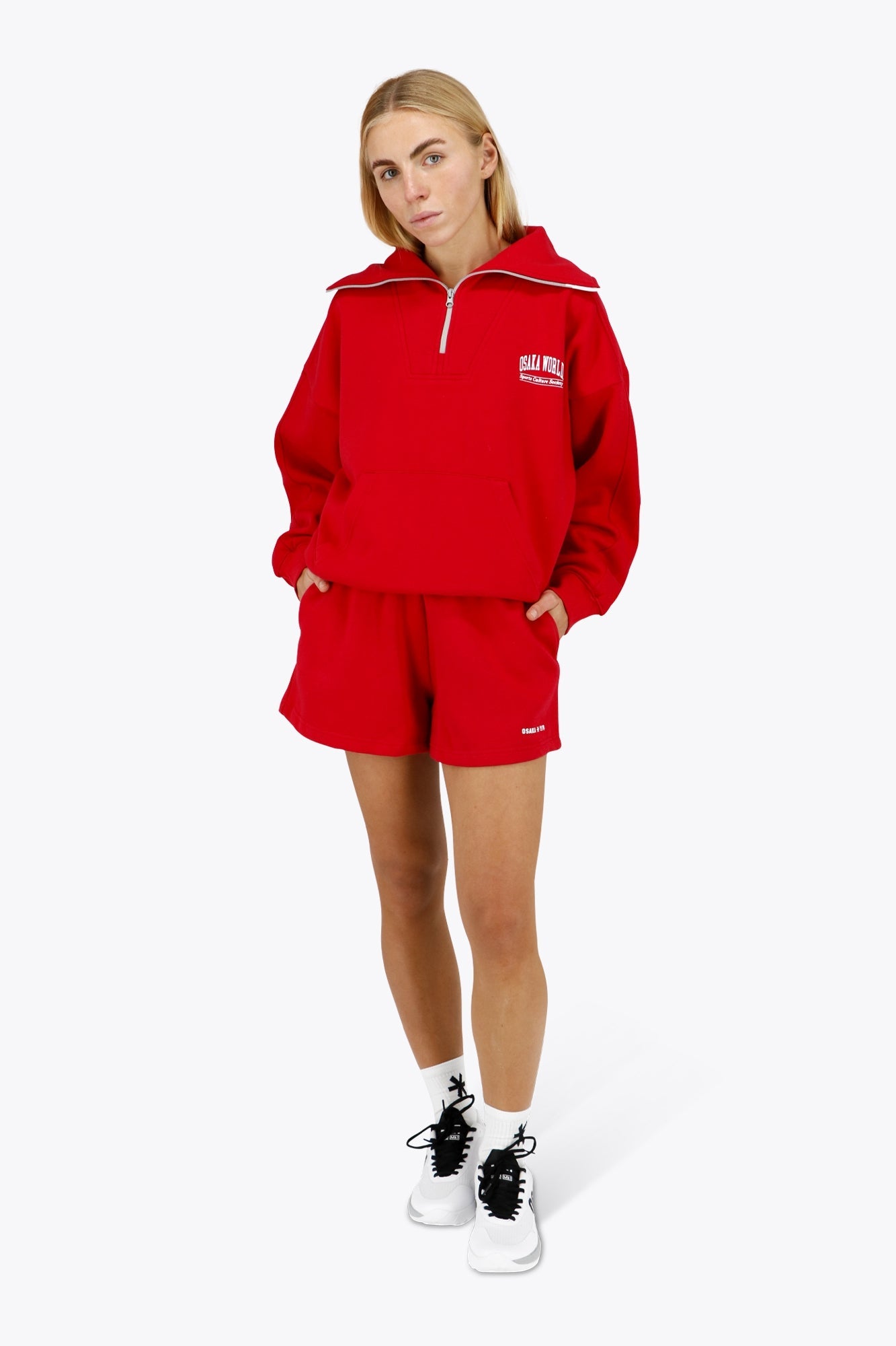 Woman wearing the Osaka women half zip sweater in red with white logo. Front view