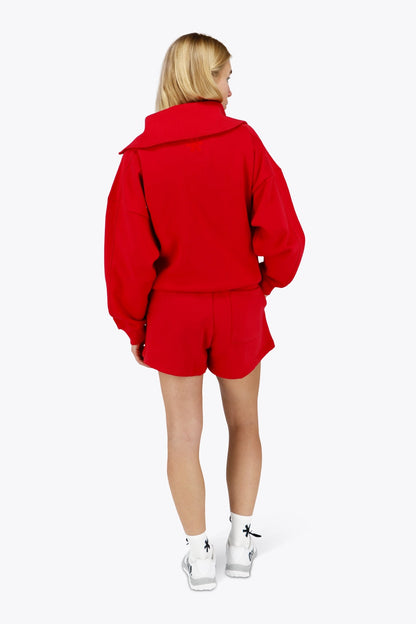 Woman wearing the Osaka women half zip sweater in red with white logo. Back view