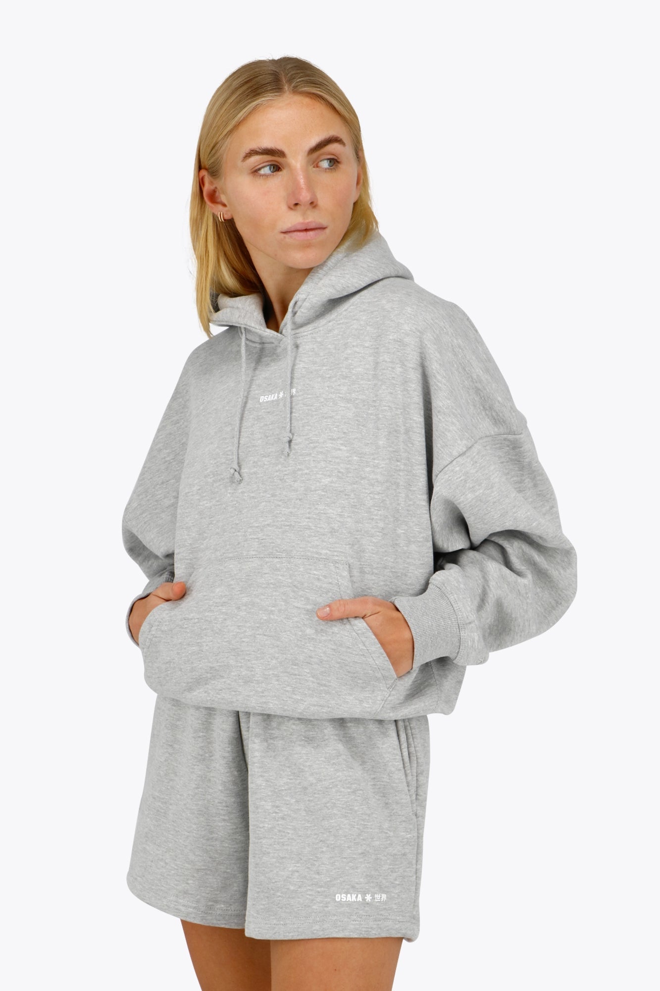 Woman wearing the Osaka women hoodie in heather grey with white logo. Front view