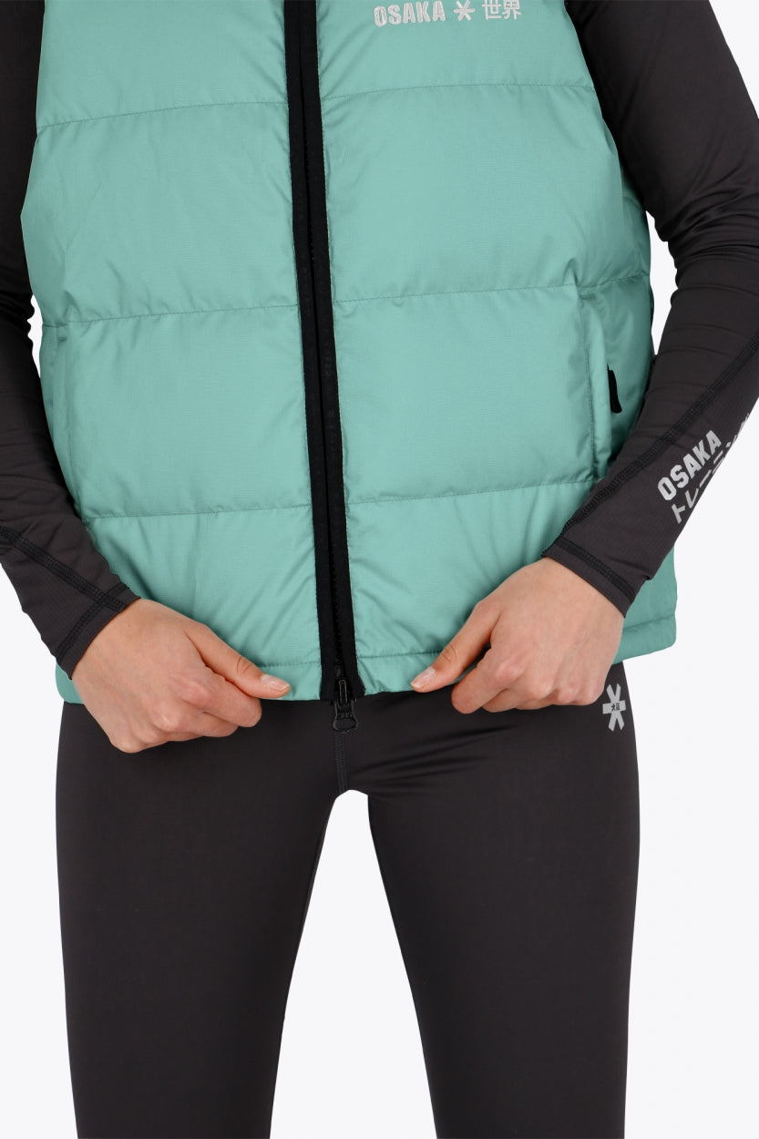 Woman wearing the Osaka women padded gilet in green with grey logo. Front detail view