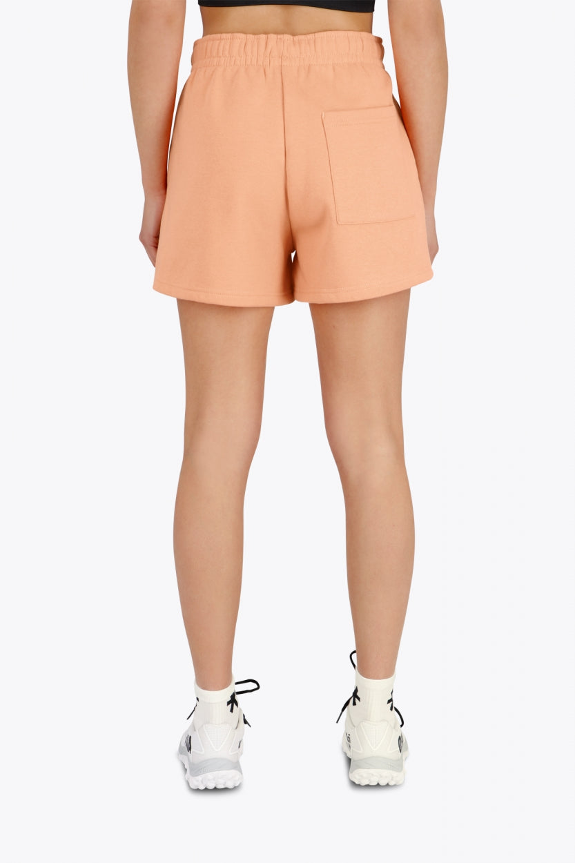 Woman wearing the Osaka women shorts in peach with logo in white. Back view