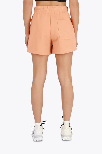 Woman wearing the Osaka women shorts in peach with logo in white. Back view