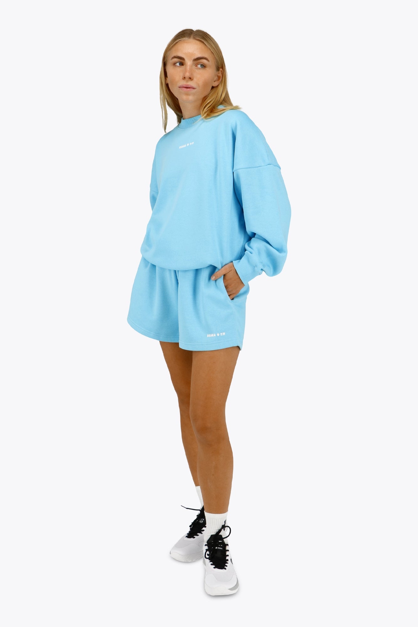 Woman wearing the Osaka women shorts in light blue with logo in white. Front view