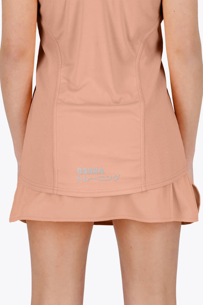 Woman wearing the Osaka women singlet in peach with logo in grey. Back view