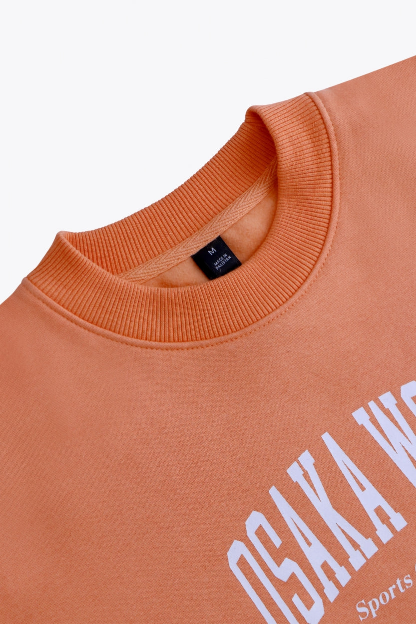 Osaka women sweater in peach with logo in white. Front flatlay neck view