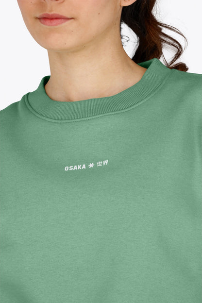 Osaka women sweater in green with logo in white. Front detail logo view