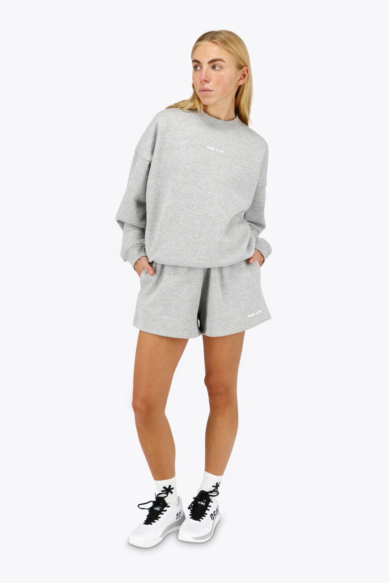 Woman wearing the Osaka women sweater in heather grey with logo in white. Front view