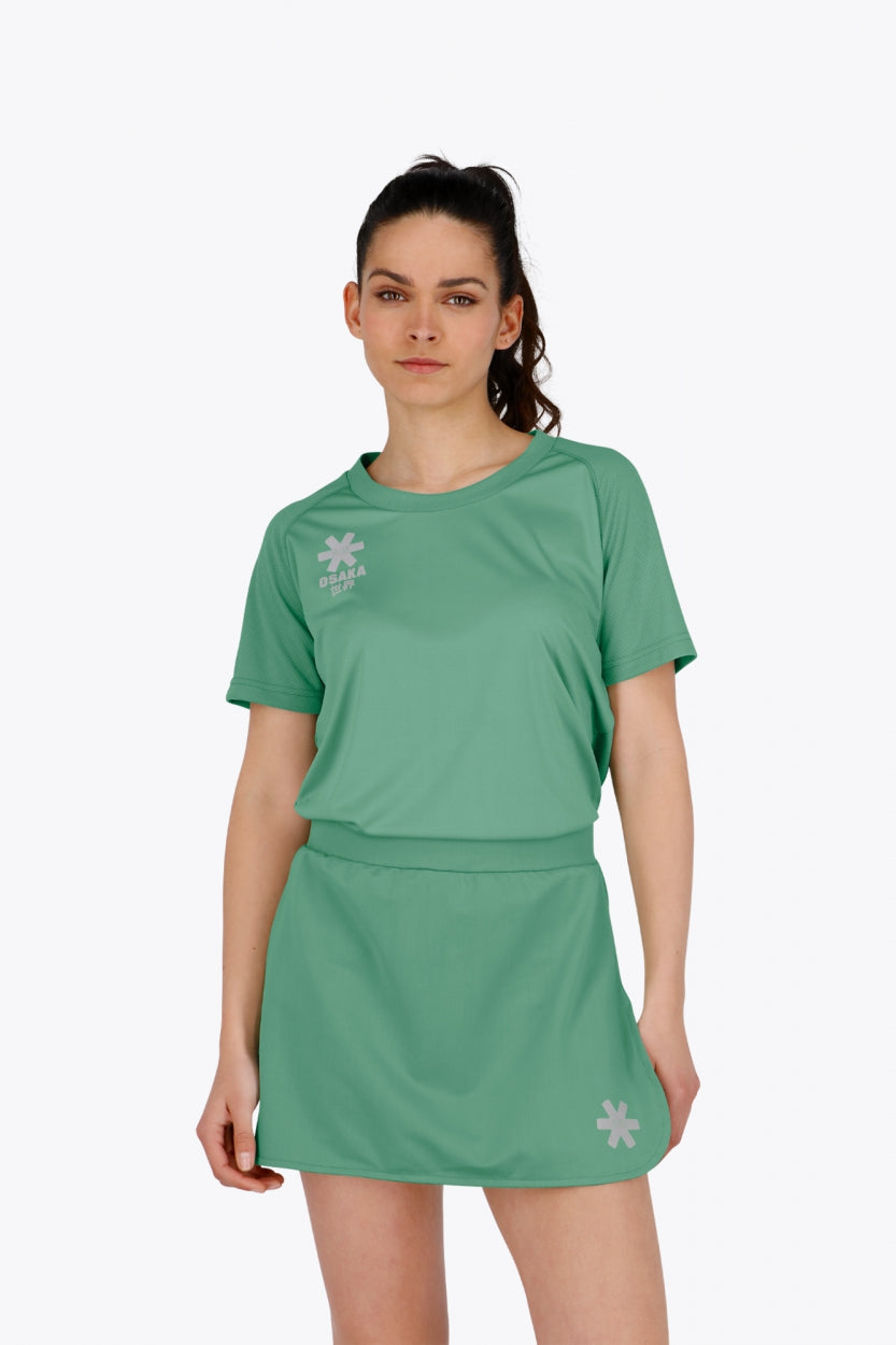 Woman wearing the Osaka women tee short sleeve in green with logo in grey. Front view