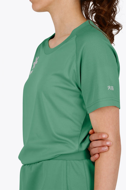 Woman wearing the Osaka women tee short sleeve in green with logo in grey. Side view