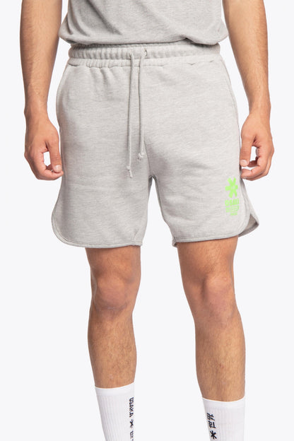 Man wearing the Osaka Men padel shorts in grey with green logo on it. Front view