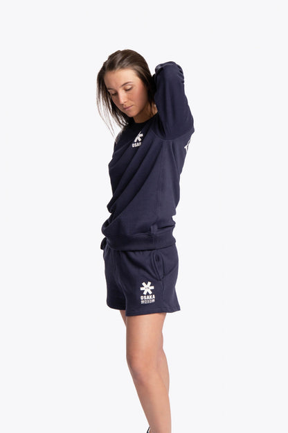 Woman wearing the Osaka navy basic unisex sweater with logo in white. Side view