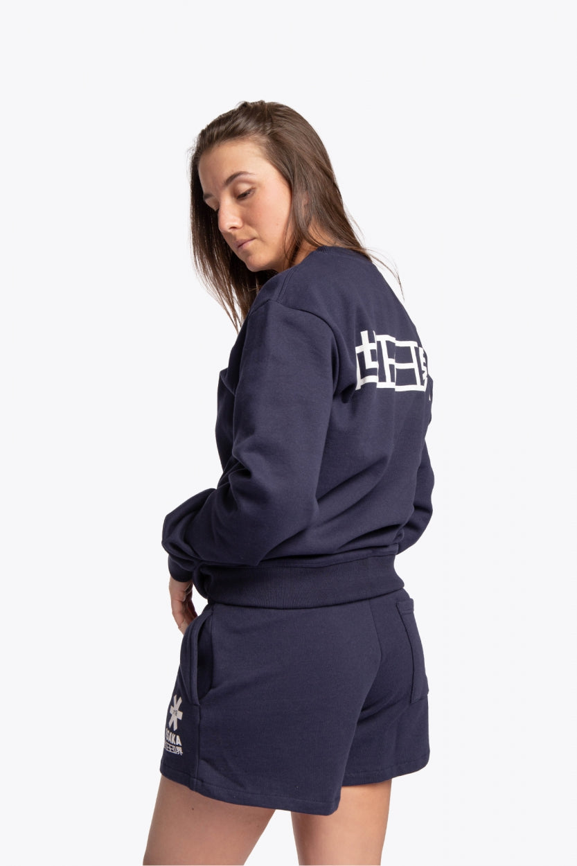 Woman wearing the Osaka navy basic unisex sweater with logo in white. Side / back view