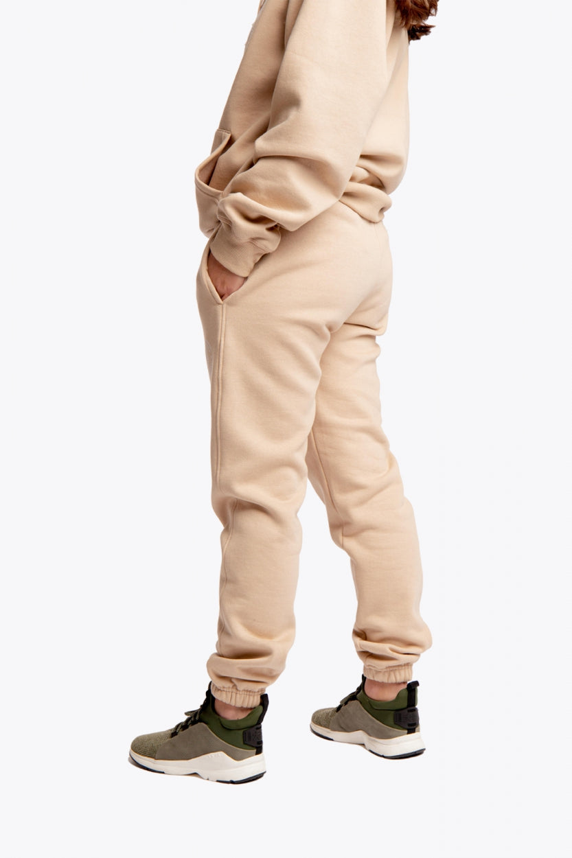 Model wearing the Osaka unisex sweatpants in stone with logo in white. Side view
