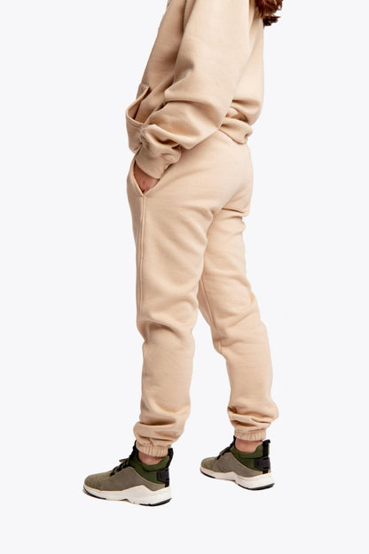 Model wearing the Osaka unisex sweatpants in stone with logo in white. Side view