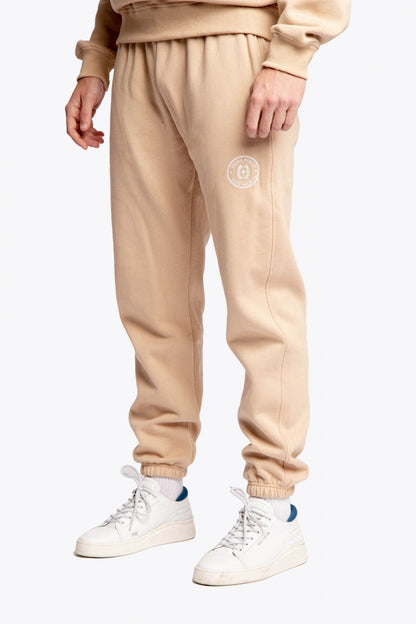Model wearing the Osaka unisex sweatpants in stone with logo in white. Side front view