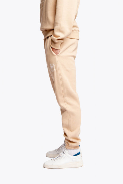 Model wearing the Osaka unisex sweatpants in stone with logo in white. Side view