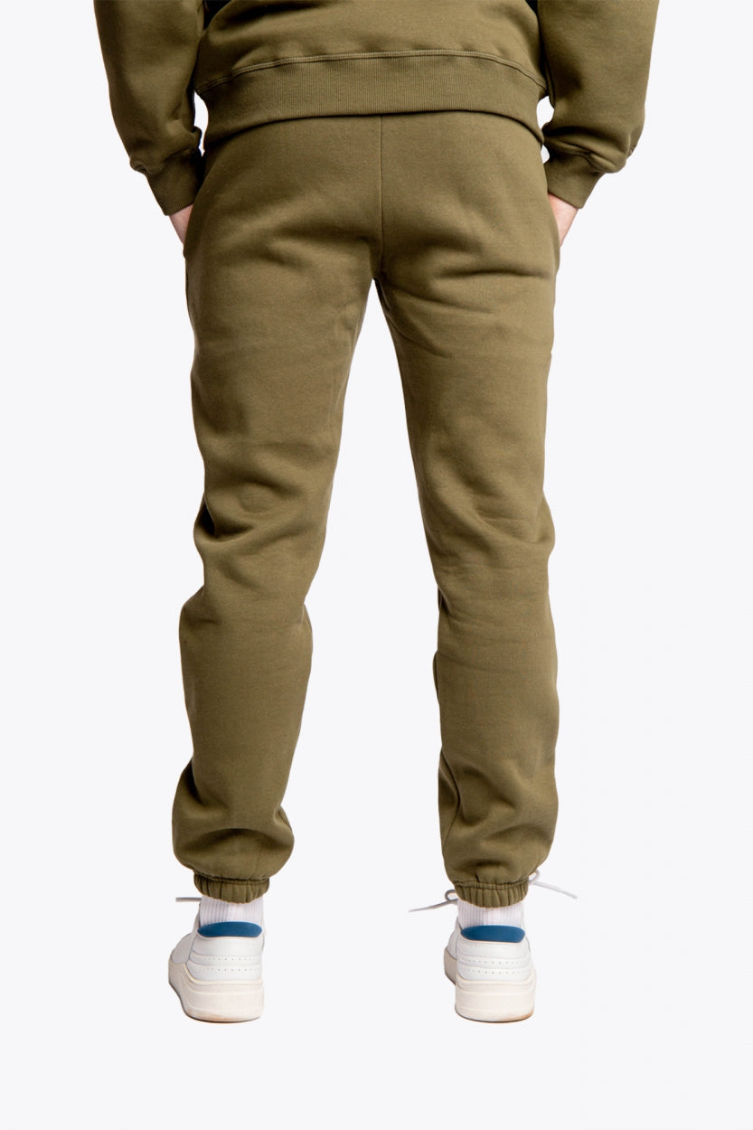 Model wearing the Osaka unisex sweatpants in army green with logo in yellow.  Back view