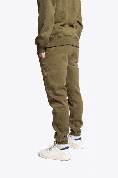 Model wearing the Osaka unisex sweatpants in army green with logo in yellow.  Back side view