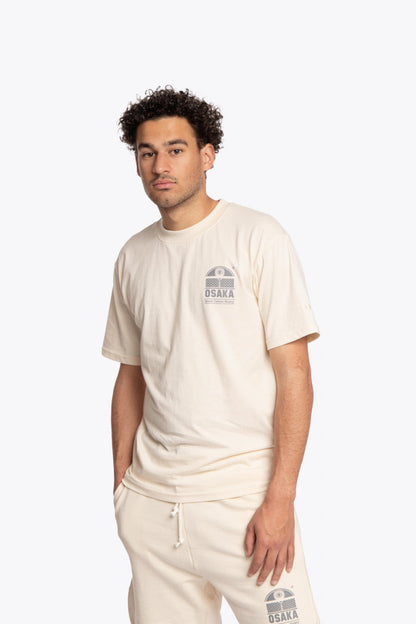 Man wearing the Osaka unisex tee in cream with logo in grey. Front view