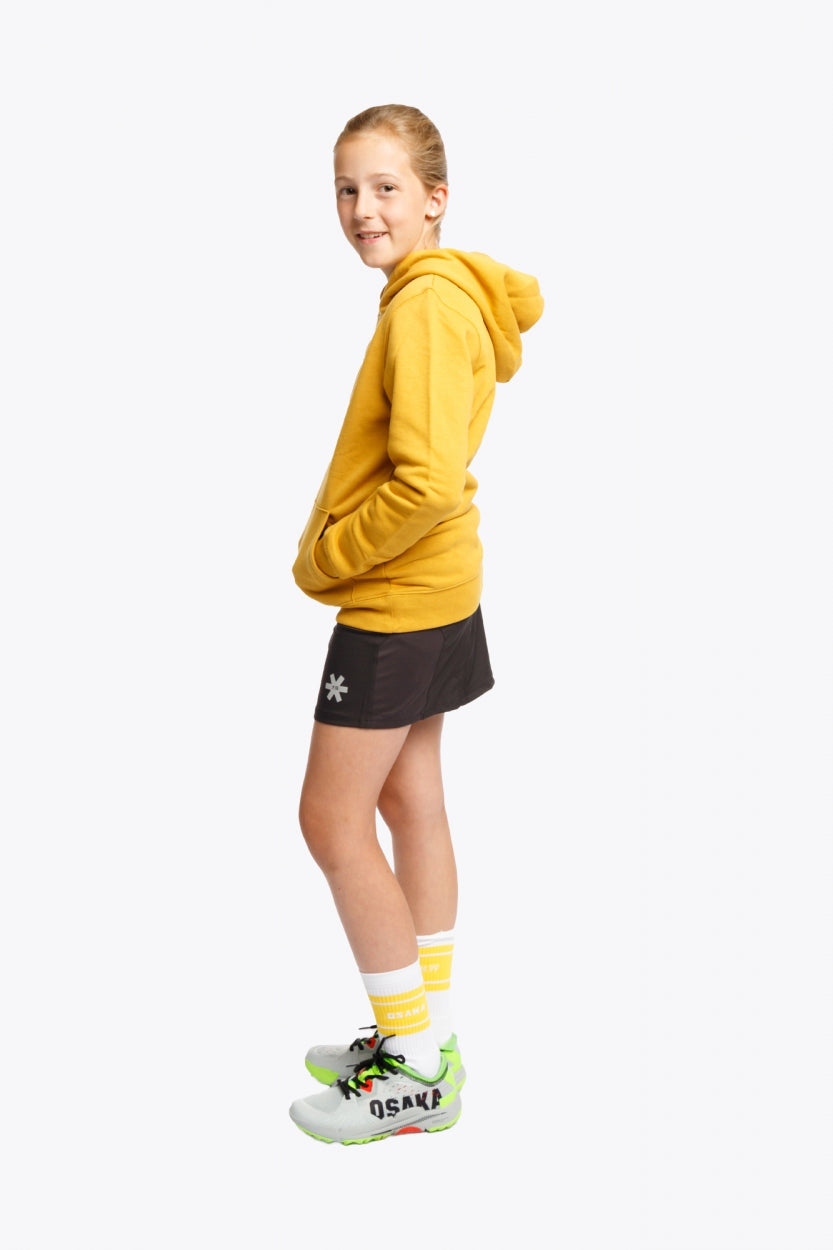 Girl wearing the Osaka kids hoodie in ochre and marker logo in white. Side view