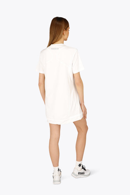 Woman wearing the Osaka women v-neck tech dress in white with logo in grey. Back view