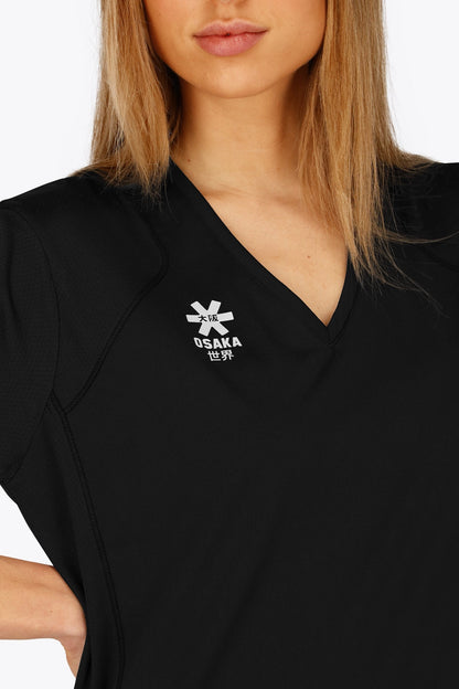 Woman wearing the Osaka women v-neck tech dress in black with logo in grey. Front detail logoview