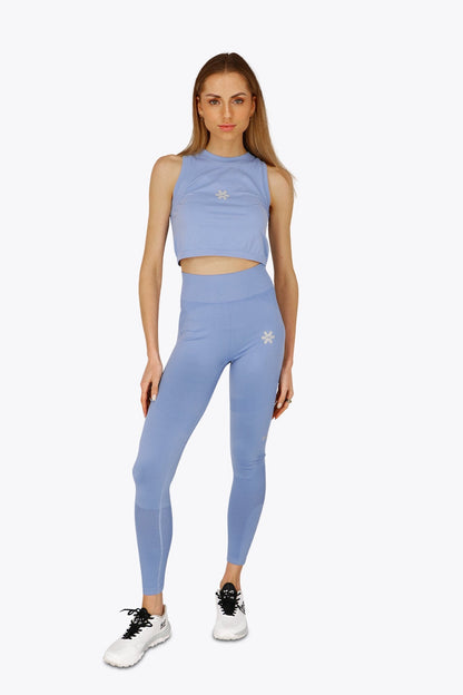 Woman wearing the Osaka women tech tank top in manor blue with logo in grey. Front view