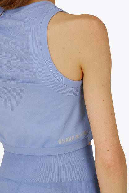 Woman wearing the Osaka women tech tank top in manor blue with logo in grey. Back detail side view