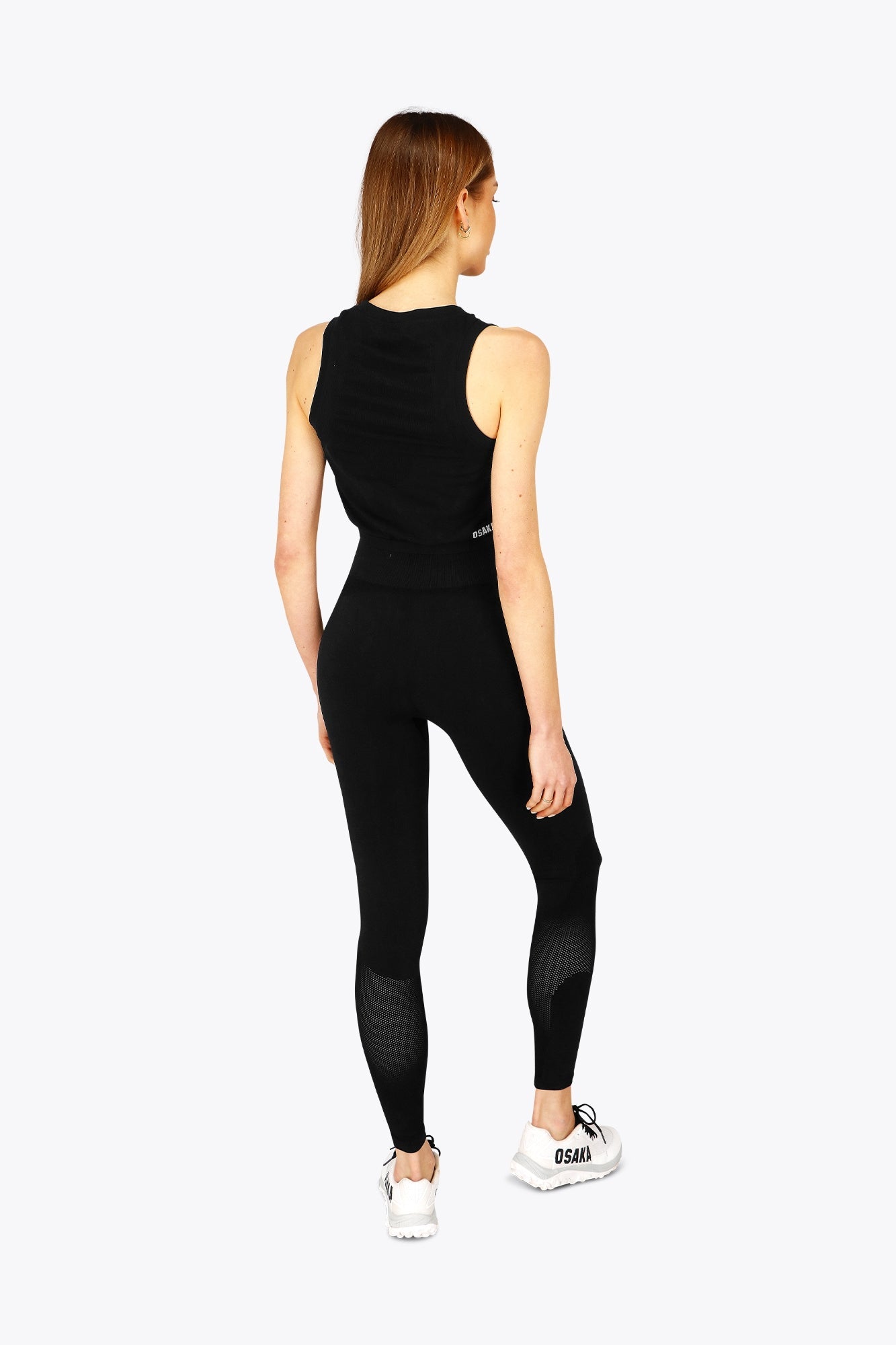 Woman wearing the Osaka women tech tank top in black with logo in grey. Back view