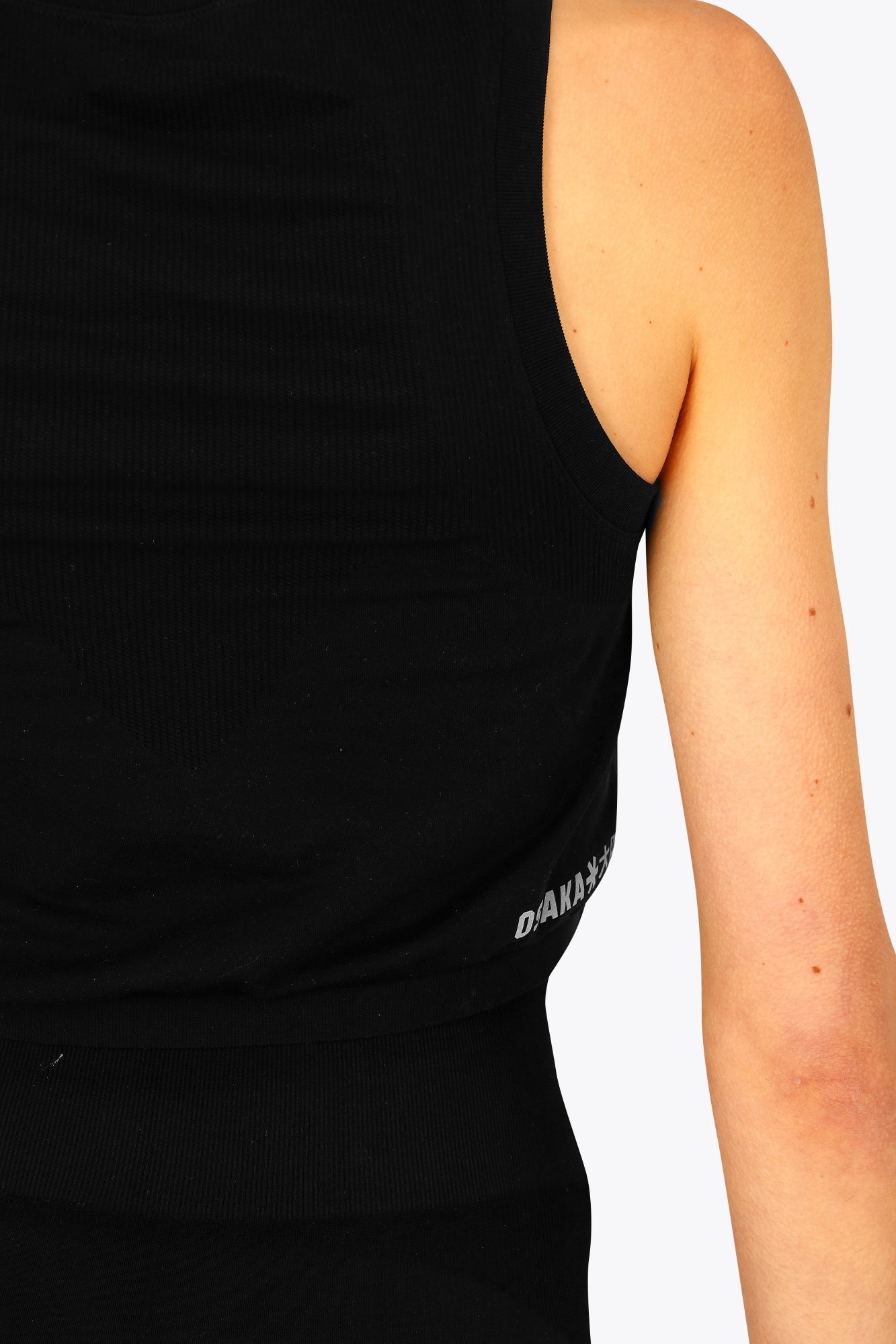 Woman wearing the Osaka women tech tank top in black with logo in grey. Back detail side view
