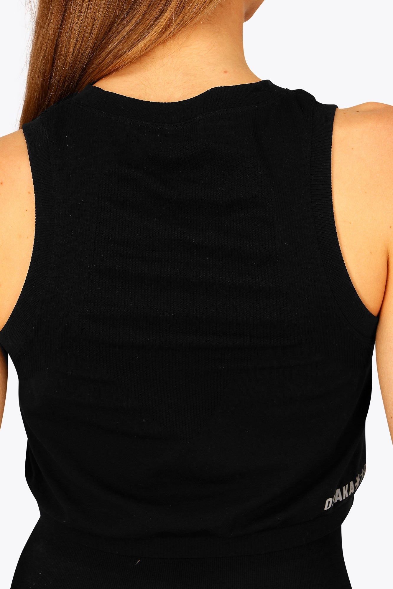 Woman wearing the Osaka women tech tank top in black with logo in grey. Back detail view