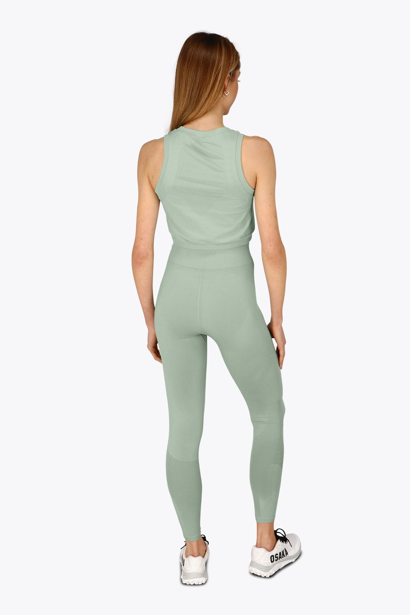 Woman wearing the Osaka women tech tank top in jadeite with logo in grey. Back view