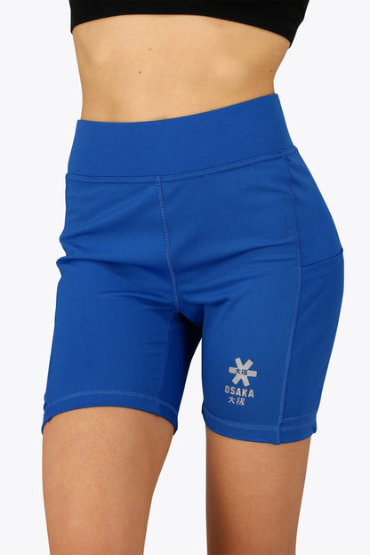 Woman wearing the Osaka women tech short thights in princess blue with grey logo. Front view