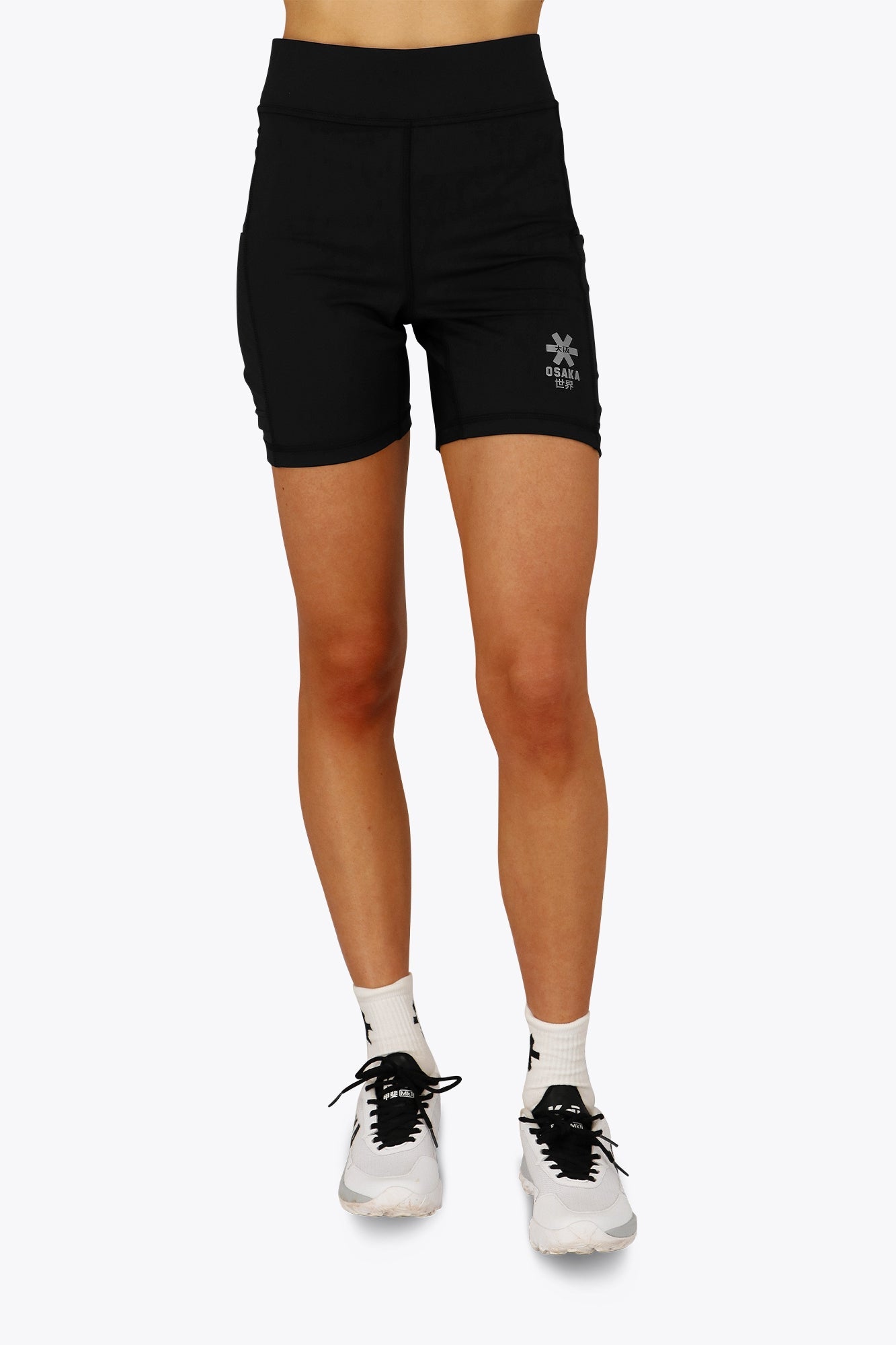 Woman wearing the Osaka women tech short thights in black with grey logo. Front view