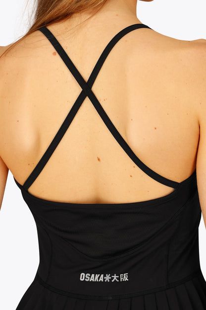 Woman wearing the Osaka women pleated tech dress in black with grey logo. Back detail cross view