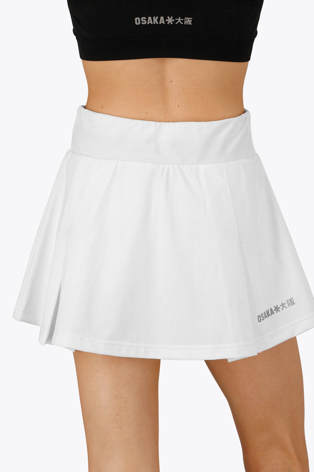 Woman wearing the Osaka women floucy skort white with logo in grey. Back view