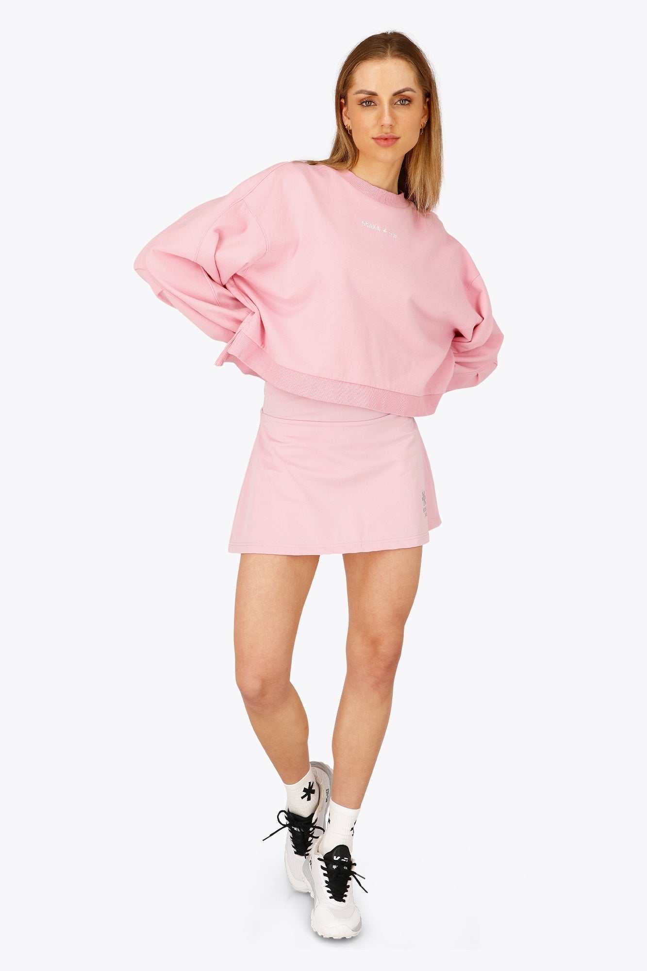 Woman wearing the Osaka women floucy skort pink with logo in grey. Front view