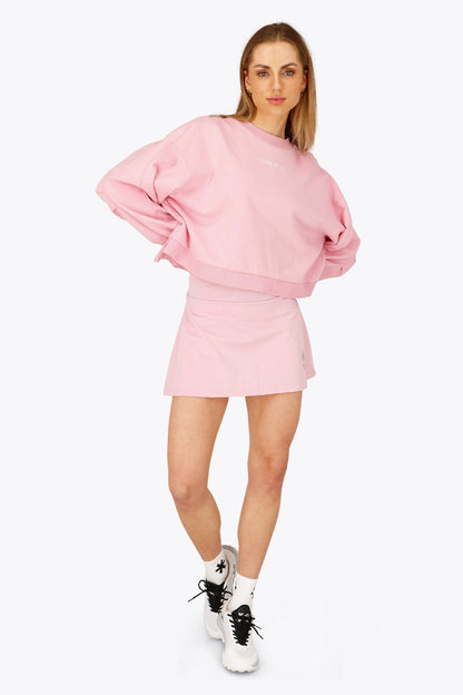 Woman wearing the Osaka women floucy skort pink with logo in grey. Front view
