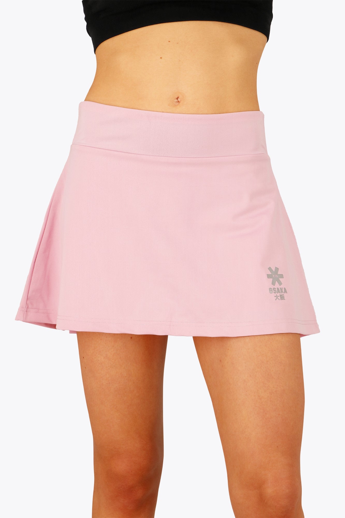 Woman wearing the Osaka women floucy skort pink with logo in grey. Front view